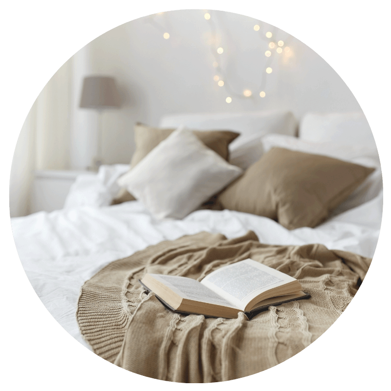 white and brown bed with pillows and twinkling lights in the background